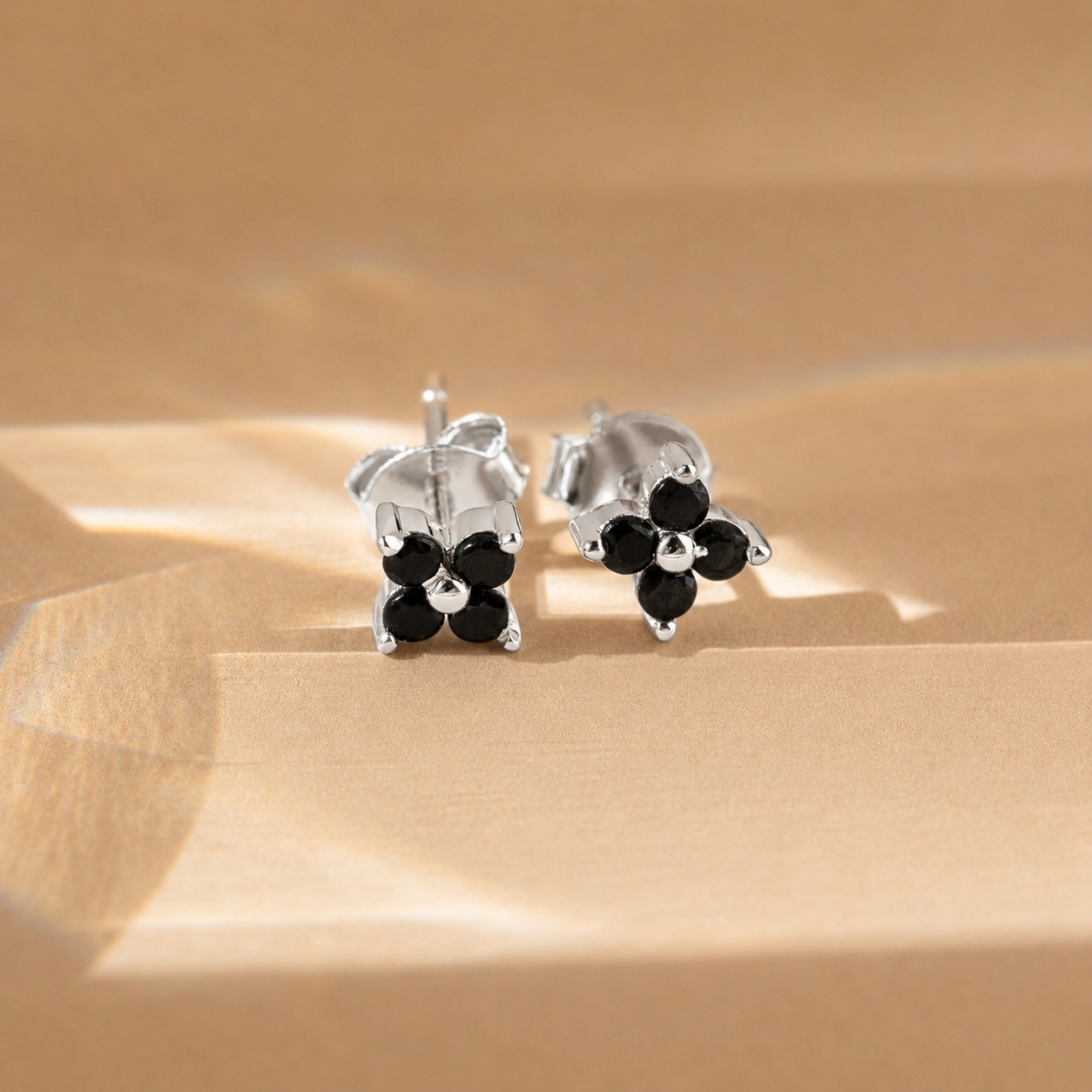 Silver earrings with black stones on a beige surface